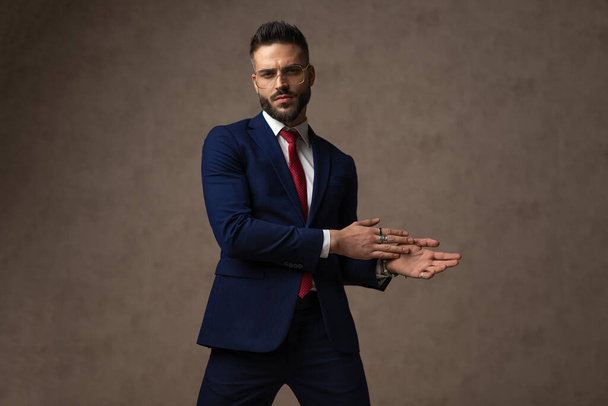 young businessman rubbing his palms and holding them aside in a fashion pose - Foto, immagini