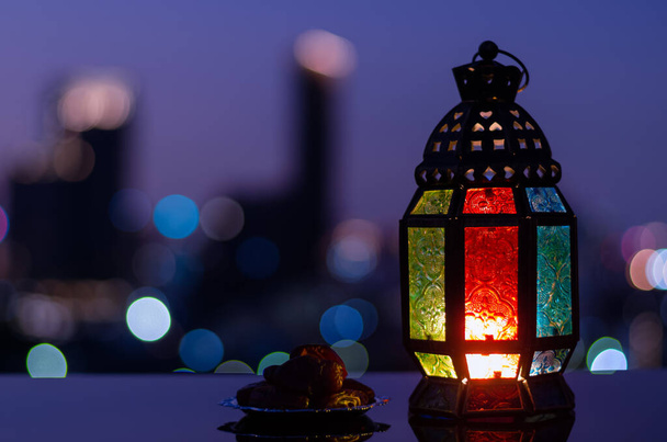Lanterna e pequeno prato de frutas datas com céu noturno e cidade bokeh fundo de luz para a festa muçulmana do mês santo do Ramadã Kareem. - Foto, Imagem