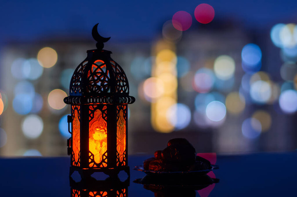 Foco seletivo de lanterna e pequeno prato de frutas datas com fundo edifício de apartamentos para a festa muçulmana do mês santo do Ramadã Kareem. - Foto, Imagem