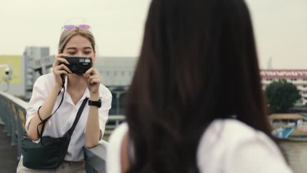Asian lesbian couples enjoying traveling using film camera taking a photo. Two beautiful young women having fun in vacation time. - Footage, Video