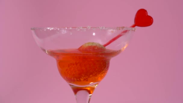 Cóctel de San Valentín con fresa en vaso de martini sobre fondo rosa - Imágenes, Vídeo