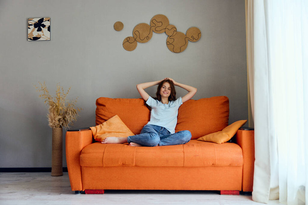ritratto di una donna sul divano arancione nella stanza di riposo in posa - Foto, immagini