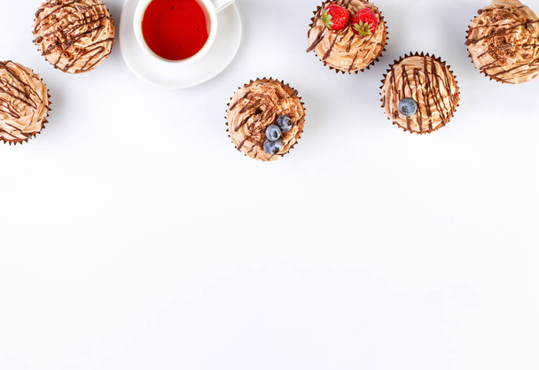 White background with chocolate cupcakes and tea, top view - Φωτογραφία, εικόνα