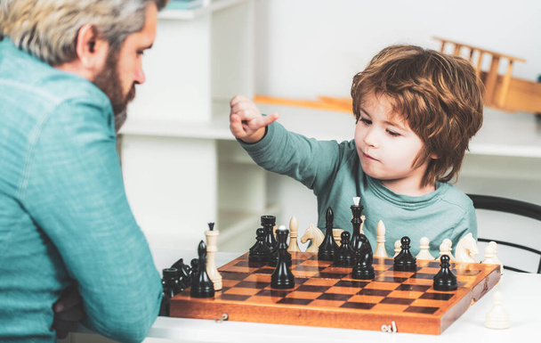 Père avec son fils jouant aux échecs à la maison. Je retourne à l'école. Père enseignant à son fils à jouer aux échecs. - Photo, image