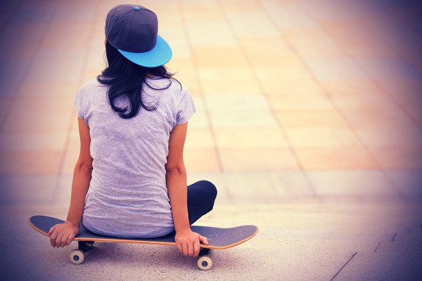 Skateboarder sit on skateboard - Photo, image