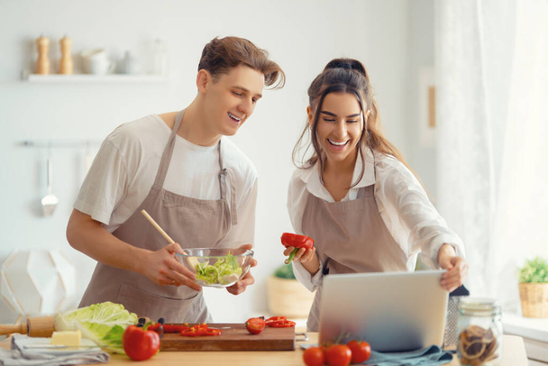 Healthy food at home. Happy loving couple is preparing the proper meal in the kitchen. - Photo, Image