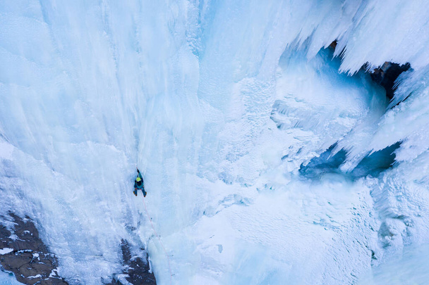 De man leidt op Ice. IJsklimmen op Frozen Waterfall, Luchtfoto. Barskoon Valley, Kirgizië - Foto, afbeelding