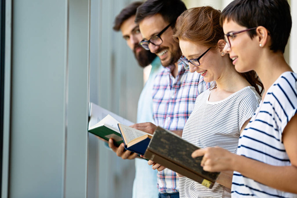Jóvenes estudiantes universitarios felices estudiando con libros en la biblioteca. Grupo de personas multirraciales en la biblioteca universitaria
. - Foto, Imagen
