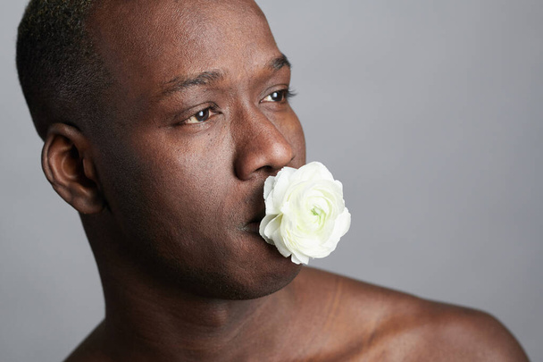 Beyaz çiçekle poz veren Afrikalı adam - Fotoğraf, Görsel