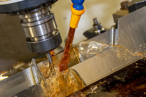 La fresadora CNC que corta las piezas del molde con el método del refrigerante del aceite. El proceso de fabricación de moldes y matrices por centro de mecanizado CNC. - Foto, Imagen
