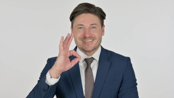 Uomo d'affari di mezza età che mostra Ok segno con le dita, sfondo bianco - Foto, immagini