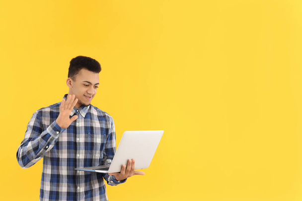 Young man with laptop on yellow background - Photo, image