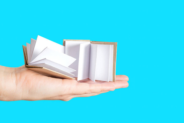 Two miniature handmade books with blank pages in hand isolated on blue background. Studying and learning concept. - Fotoğraf, Görsel