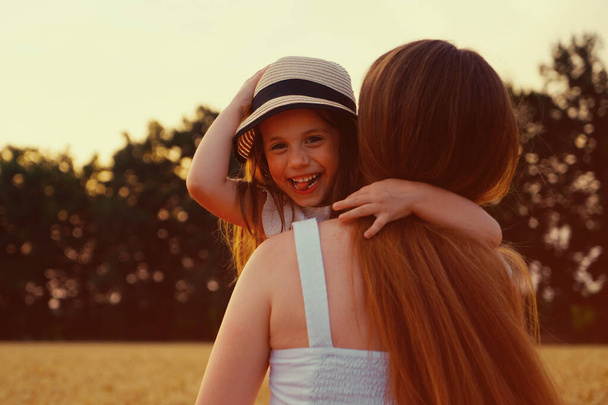 Mom running in field with happy daughter in arms - Photo, image