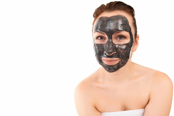 hermosa mujer de mediana edad con una máscara de arcilla limpiadora en su cara, el concepto de cosméticos y el cuidado de la piel facial femenina más antigua - Foto, imagen