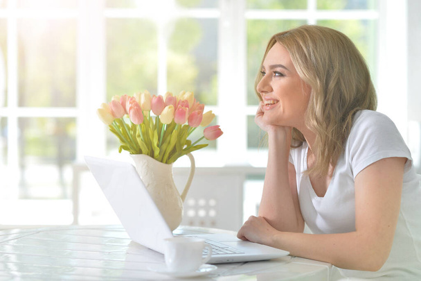  young beautiful woman   using laptop at table with flowers - Foto, Bild