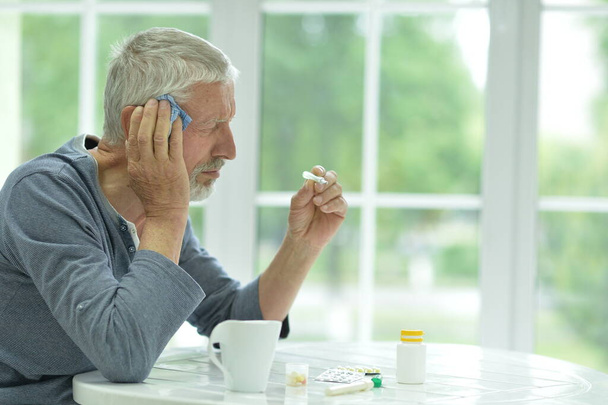 Portrait of sad sick senior man  with thermometer - Фото, зображення