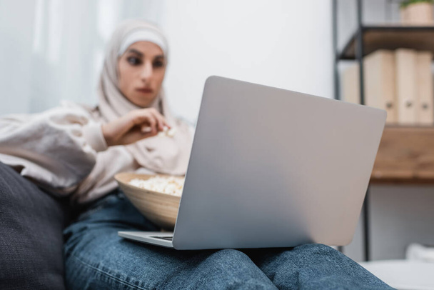 selective focus of laptop near blurred muslim woman watching movie at home - Valokuva, kuva