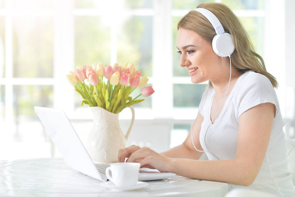  young woman   with headphones  using laptop  - Фото, изображение