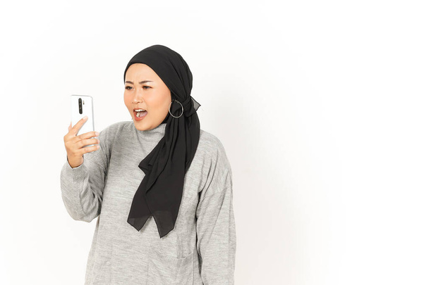 Rozzlobený na video volání krásné asijské ženy na sobě hidžáb izolované na bílém pozadí - Fotografie, Obrázek