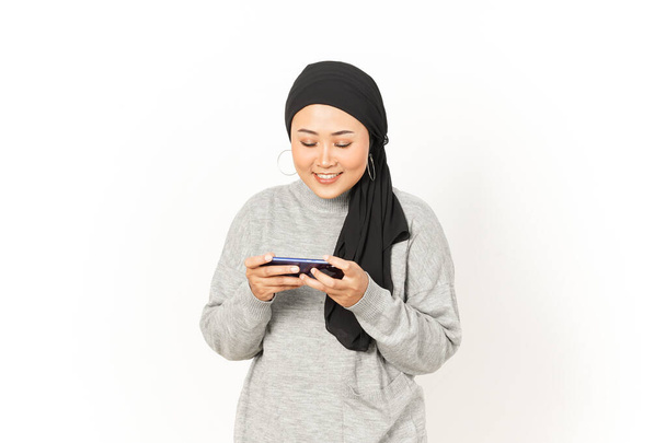 Pelaaminen mobiili peli älypuhelimella kaunis aasialainen nainen yllään Hijab eristetty valkoisella taustalla - Valokuva, kuva