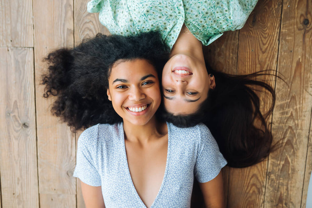 Zwei junge Frauen liegen Kopf an Kopf auf dem Boden - Foto, Bild