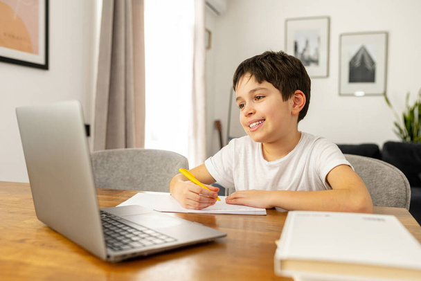 Smiling schoolboy studying on the distance from home, using trendy laptop - Photo, image