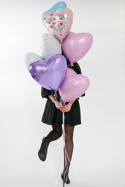 Kobieta Holding zestaw balonów żelowych powietrza różowe i fioletowe kolory na imprezę Walentynki na białym tle. - Zdjęcie, obraz