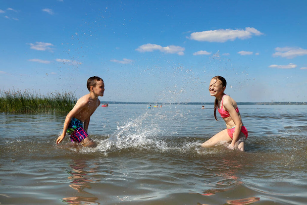 A boy and a girl play together in the lake in the summer. - Фото, зображення