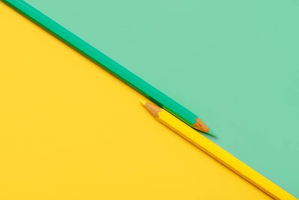 Yellow and green pencil placed on yellow and green paper background with copy space for your image or text - Photo, image