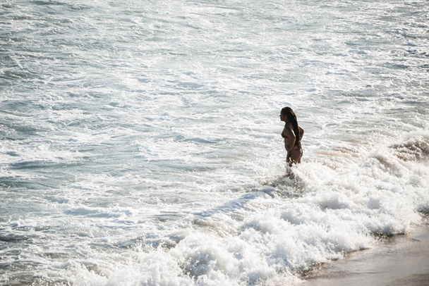 Salvador, Bahia, Brazil - September 05, 2021: A person entering the sea from Praia da Paciencia in Salvador, Bahia, Brazil. - Zdjęcie, obraz