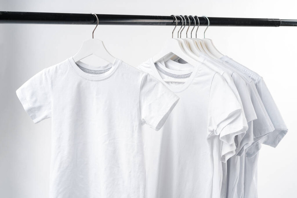 Clothes hang on clothing rack over white background. - Фото, зображення