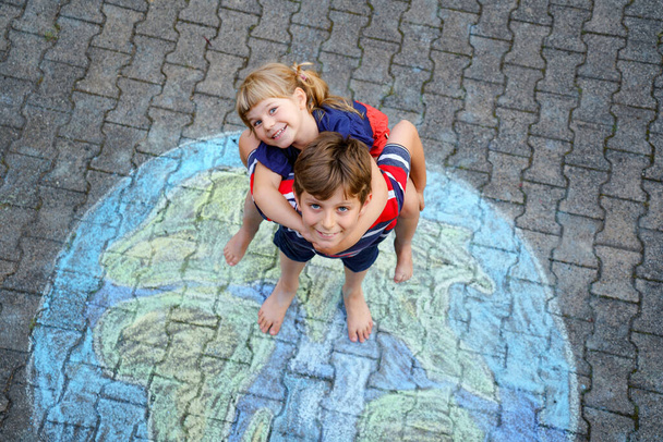 Niña preescolar y niño de la escuela con la pintura globo de tierra con tiza de colores en el suelo. Feliz concepto del día de la tierra. Creación de niños para salvar el mundo, el medio ambiente y la ecología. - Foto, Imagen