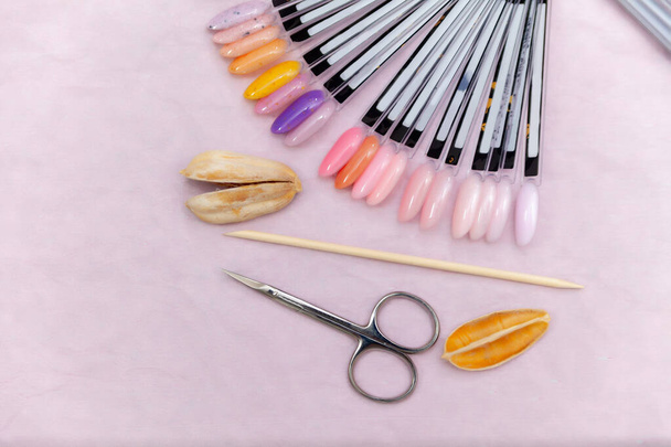 Nagelstudio-Tisch mit Maniküre-Werkzeugen und Nagellackflaschen auf rosa Hintergrund. Flache Lage, Draufsicht. Schönheitsbehandlungskonzept - Foto, Bild