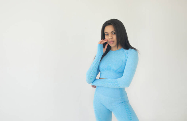 young fit african american woman in blue sportswear looking at camera on grey background - Foto, afbeelding