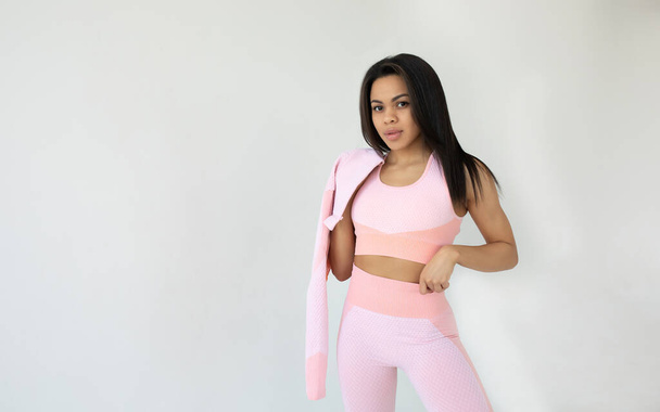 attractive young fit african american woman in pink sportswear looking at camera and posing on grey background - Fotó, kép