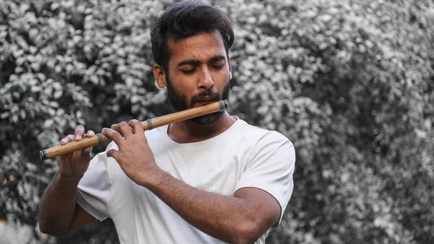 Bansuri játékos játszik zenét a napsütésben a Park - Indian Flute Player - Fotó, kép