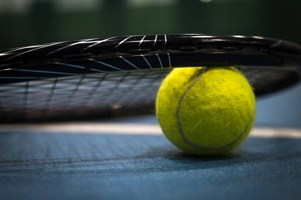 Sárga tenisz labda közelkép ütő alatt a kék kemény tenisz pályán. - Fotó, kép