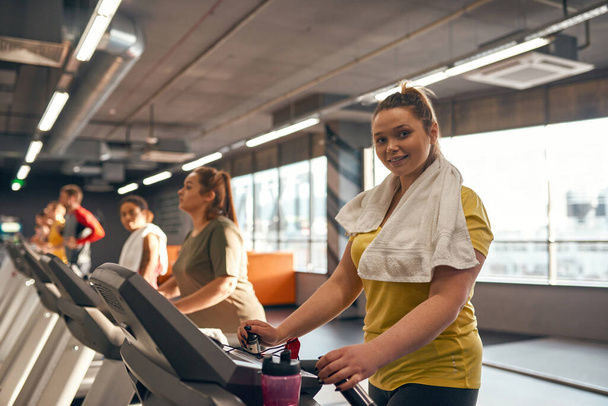 Focus on girl run on treadmill and look at camera - Φωτογραφία, εικόνα