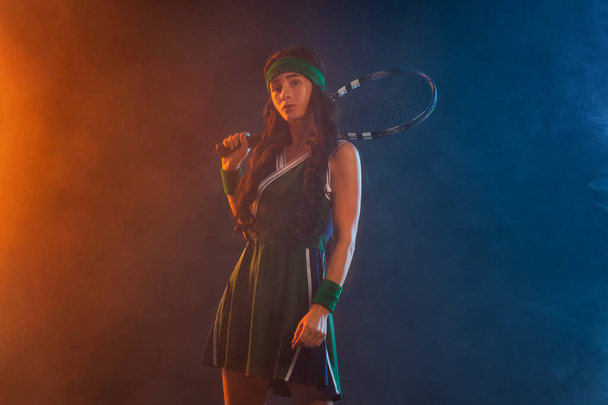 Tennis player with racket in sportswear. Woman athlete playing dark background. - Фото, зображення