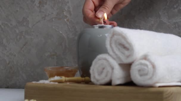 Spa massaggio casa di cura relax. Asciugamani candele bianche scrub argilla sale si trovano su un vassoio su uno sfondo grigio con spazio per il testo. - Filmati, video