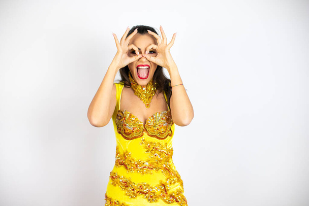 Young beautiful woman wearing carnival costume over isolated white background doing ok gesture shocked with smiling face, eye looking through fingers - Photo, Image