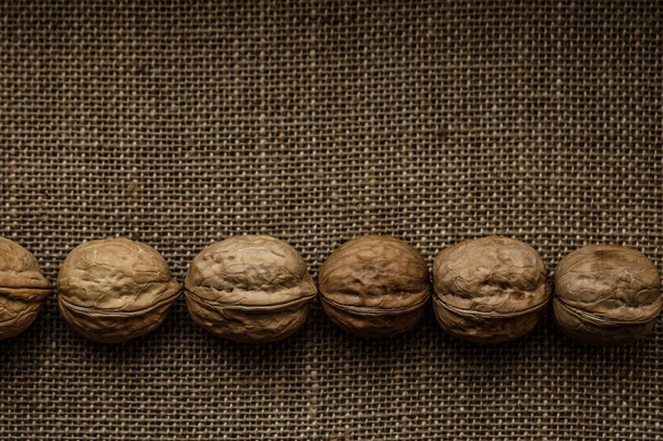 walnuts on the fabric burlap whole. empty copy space for inscription. Food background.  - Фото, изображение