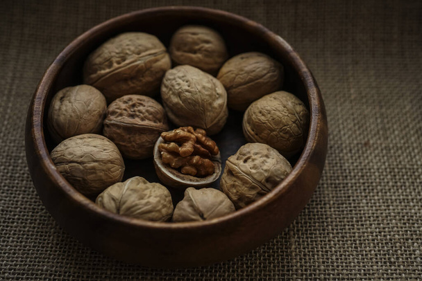 one half of walnut and nuts in a wooden bowl. close-up image. sackcloth on background.  - Foto, Imagen