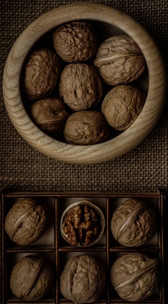 whole walnuts  lie in a square cell. In neighboring cells, fill in nuts. Showcase store. Sackcloth background. shelled  nut in the middle. - Foto, Imagen