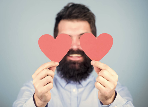 That is love. Sexy valentine man covering eyes with love cards. Bearded man holding red hearts. Hipster with small hearts. Happy valentines day. Expressing his love - Фото, изображение
