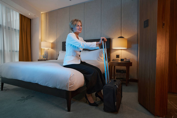 Senhora alegre desfrutando de sua estadia no hotel durante uma viagem de negócios - Foto, Imagem