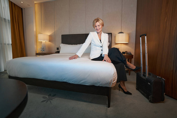 Zufriedene Geschäftsfrau genießt Erholung in ihrem Hotelzimmer - Foto, Bild