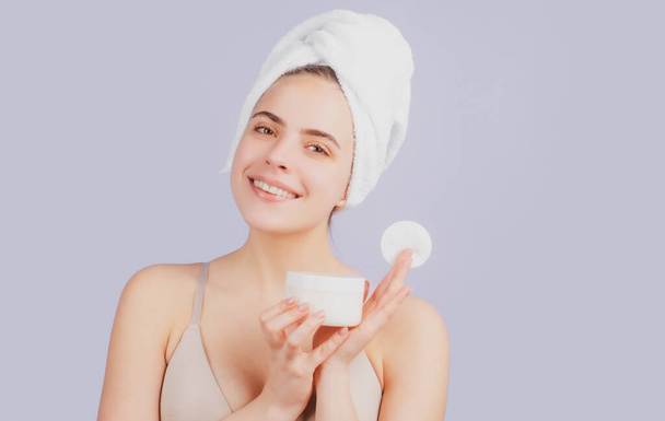 Beauty woman. Cosmetic cream on woman face with clean soft skin. Beautiful girl with a towel on head, facial treatment, cosmetology, beauty and spa. - Foto, afbeelding