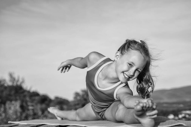 痛みは得られない。体操だ。空を背景に幸せな10代の女の子。子供には柔軟な体がある。スポーツウェアの訓練中の子供。拡大し温暖化するという概念です。子供の頃の幸せ。健康とフィットネス - 写真・画像
